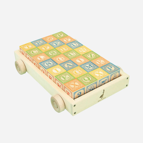 Colorful alphabet blocks on a wooden pull cart with a light green background